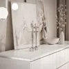 A white dresser with decorative items on top, including framed artwork, a bowl, a vase with branches, and two ballet dancer figurines. Produktbild-Vorschau