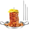 A vertical rotisserie grill with meat and pineapple on top, placed in a metal pan with some sausages, and three metal skewers standing next to it. Produktbild-Vorschau