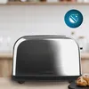 A stainless steel toaster sits on a wooden countertop in a kitchen setting. There's a hint of a pastry to the right. Anteprima dell’immagine prodotto