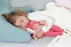 A young girl is sleeping with a baby doll in her arms. Náhľad obrázku produktu