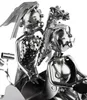 A close-up of a metal sculpture of a wedding couple on a tractor. Produktbild-Vorschau