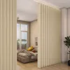 A bedroom divided by a beige vertical blind curtain, with a bed visible in the background. Náhled obrázku produktu