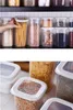 A collection of clear plastic food storage containers filled with various dry goods, neatly arranged on shelves and a countertop. Anteprima dell’immagine prodotto