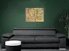 A map of Middle-earth is displayed on a dark green wall above a gray sofa. A small white and black table is in the foreground. Náhled obrázku produktu