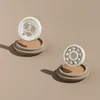 Two white wheels, one a bearing and the other a spoked wheel, are displayed on beige circular stands against a light beige background. Náhled obrázku produktu
