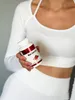 A person in white athletic wear holds a bottle of Berberine supplement. Produktbild-Vorschau
