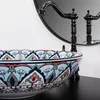 A close-up shot of a decorative vessel sink with a faucet and mirror in the background. Náhled obrázku produktu