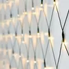 A close-up, angled view of a net of small, warm white LED lights against a white wall. Produktbild-Vorschau