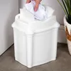 A hand is shown throwing crumpled paper into a white trash can. Produktbild-Vorschau