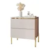 A modern bedside table with two drawers and golden legs, decorated with a vase of dried flowers and perfume bottles. Náhľad obrázku produktu