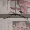 A close-up of a gift-wrapped item with a bow and floral imagery. Produktbild-Vorschau