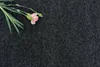 A single pink carnation with green leaves rests on a dark gray textured surface. Produktbild-Vorschau