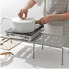 A person is using a shelf organizer to hold a portable induction cooktop with a pot on it. Produktbild-Vorschau