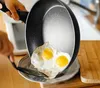 A person is pouring fried eggs from a frying pan onto a plate. Náhled obrázku produktu