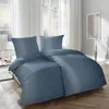 A neatly made bed with blue bedding, set in a bright bedroom with large windows and sheer curtains. Produktbild-Vorschau