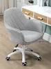 A gray office chair with a white base and wheels is shown in a room with a desk in the background. Náhľad obrázku produktu