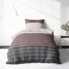 A neatly made bed with striped bedding in a room with soft lighting. Produktbild-Vorschau
