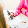 A person in a pink shirt is using a scanning pen to read a book. Náhľad obrázku produktu