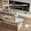 A white dehumidifier is placed in a modern living room with a sofa and coffee table. Podgląd zdjęcia produktu