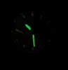 A close-up view of a watch face in the dark, with luminous hands and markers. Voir les images du produit