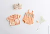 Flat lay of baby clothes and a small sprig of baby's breath. Produktbild-Vorschau