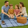 A family having a picnic on a checkered blanket in a grassy area. Anteprima dell’immagine prodotto