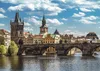 A scenic view of the Charles Bridge in Prague, with historic buildings and a river in the foreground. Náhled obrázku produktu