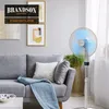 A standing fan is placed next to a grey sofa in a modern living room. Náhled obrázku produktu