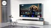 A modern living room with a large TV displaying a streaming service interface, a soundbar on a media console, and a tablet on a coffee table. Anteprima dell’immagine prodotto