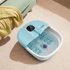 A blue foot spa with water and bubbles is placed on a beige carpet next to a folded yellow blanket and a portion of a green chair. Anteprima dell’immagine prodotto