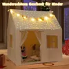 A child's play tent decorated with star lights and string lights, set up indoors with Christmas decorations in the background. Podgląd zdjęcia produktu