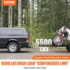A black pickup truck is towing a trailer with a dirt bike on it, in a wooded area. Produktbild-Vorschau