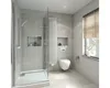 A modern, minimalist bathroom with a wall-hung toilet, a glass-enclosed shower, and a tall radiator. Anteprima dell’immagine prodotto