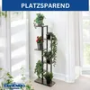 A multi-tiered plant stand filled with various potted plants, placed indoors near a window with sheer curtains. Produktbild-Vorschau
