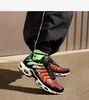 A person wearing black pants and colorful Nike sneakers, standing on a paved surface. Anteprima dell’immagine prodotto