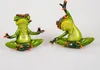 Two green frog figurines in yoga poses, sitting on a white background. Produktbild-Vorschau