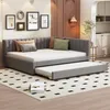 A modern living room with a grey upholstered daybed with a pull-out trundle bed, decorated with throw pillows. The room also features framed artwork on the wall and a small side table with a lamp. Náhľad obrázku produktu