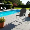 A folding chair is placed on a patio next to a swimming pool. Produktbild-Vorschau