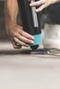 A person's hands are shown adjusting the base of a black and blue object on a textured surface. Produktbild-Vorschau