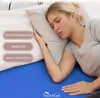 A woman sleeping on a bed with a blue sheet and a pillow. Produktbild-Vorschau