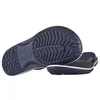 The underside of two navy blue Crocs flip-flops are shown against a white background. One flip-flop is angled to show the sole, while the other is placed in front and slightly to the side, also showing its sole. Produktbild-Vorschau