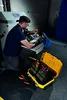 A man is working on some equipment with tools laid out. Voir les images du produit