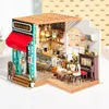 A miniature model of a coffee shop called Simon's Café, with detailed interior and exterior elements. Anteprima dell’immagine prodotto