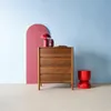 A wooden dresser with red decorative items against a backdrop of pink and light blue walls. Anteprima dell’immagine prodotto