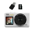 A white digital camera with accessories (USB drive and SD card) displayed against a white background. Produktbild-Vorschau