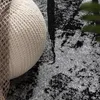 A close-up view of a textured rug with a woven pouf partially visible. Produktbild-Vorschau