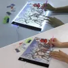 A split image showing a person doing diamond painting on an LED light pad. The top half shows the light pad illuminated, and the bottom half shows it unlit. Náhled obrázku produktu