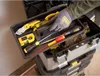 A person's gloved hand is placing a tool into a toolbox. Voir les images du produit