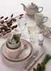 A table setting with a teapot, cup, glasses, plates, cutlery, and decorative elements. Produktbild-Vorschau