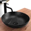 A black marble-patterned vessel sink with a black faucet is shown on a wooden countertop. Anteprima dell’immagine prodotto